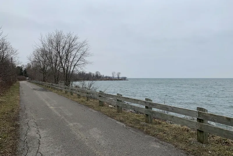 A Lake Ontario waterfront trail at Ajax–Pickering with a wooden guardrail under a grey sky.